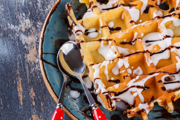 waffles drizzled with chocolate and cream served with two spoons